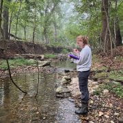 HEADWATERS — Kathleen Cutting takes stream monitoring notes on Brush Creek, a headwater stream of the White River and part of the Beaver Lake watershed.
