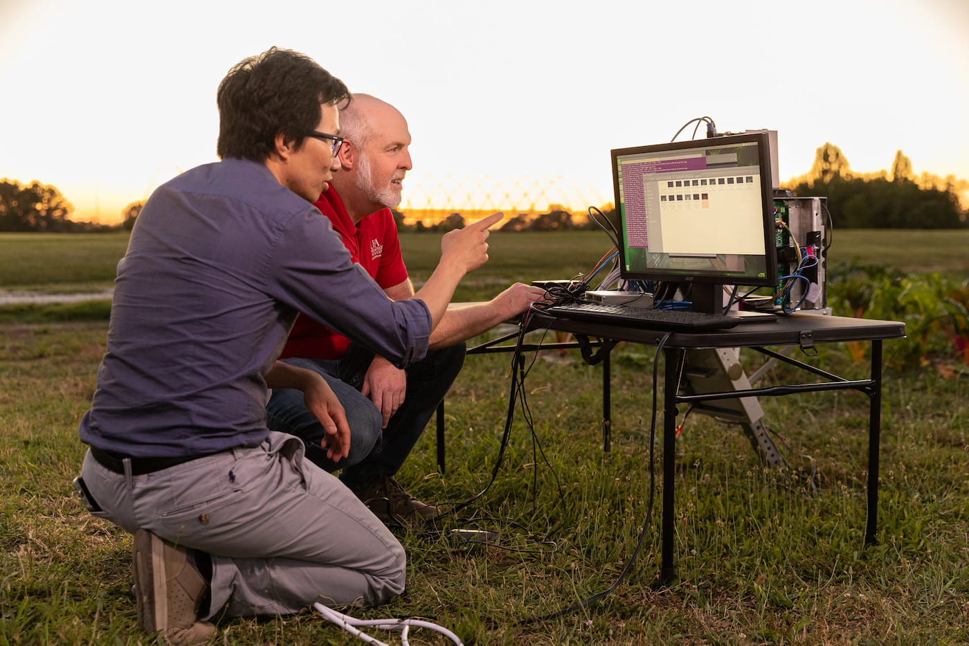 Division of Agriculture professor of entomology Ashley Dowling, right, and Khoa Luu, assistant professor of computer science and computer engineering, test out the AI-powered smart insect trap, developed in collaboration with ag-tech company SolaRid AR