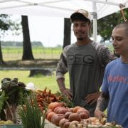 CAFF students Gabriel Barragan (light blue shirt) and Ryan Tanksley (green shirt), with CAFF instructor Joe Hannan, sell produce grown by CAFF program students. The market is open Wednesdays in July and August at AGRI Park in Fayetteville. (U of A System Division of Agriculture photo by Fred Miller)