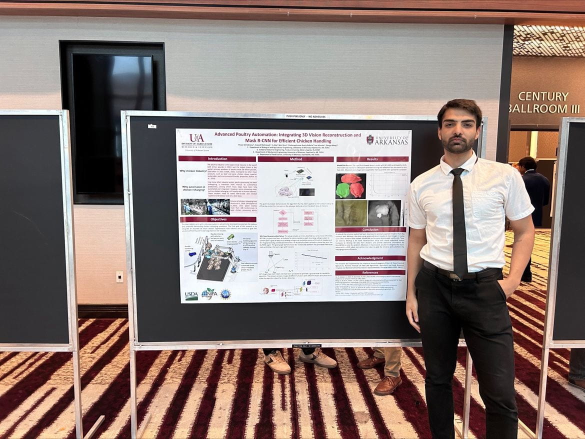 Pouya Sohrabipour, BAEG student, stands next to his research poster.