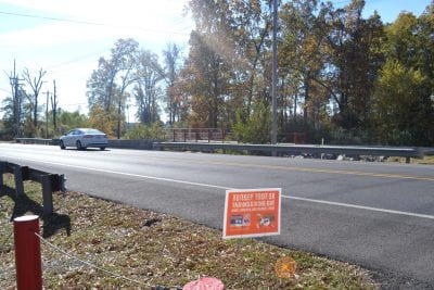 A car drives along a highway where at the side of the road a sign advertises the turkey trot 5k