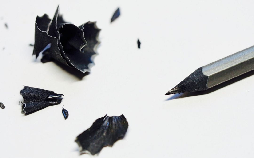 Black pencil and shavings against a white background.