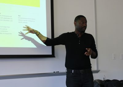 A man gestures at a powerpoint slide.