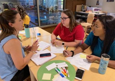 Three women sit at a table writing on paper and talking during the September Professional Educator Development Day at the Jean Tyson Child Development Study Center at the University of Arkansas.