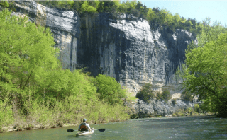 A man kayaking under large bluffs on the Upper Buffalo River.