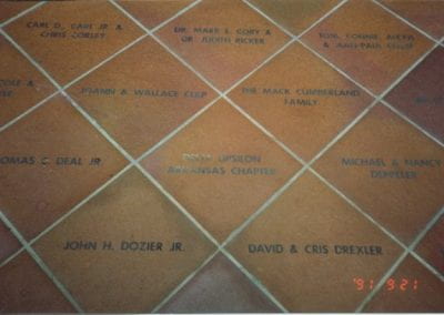 A brown floor tile with "Delta Upsilon Arkansas Chapter" on it and other surrounding named tiles.